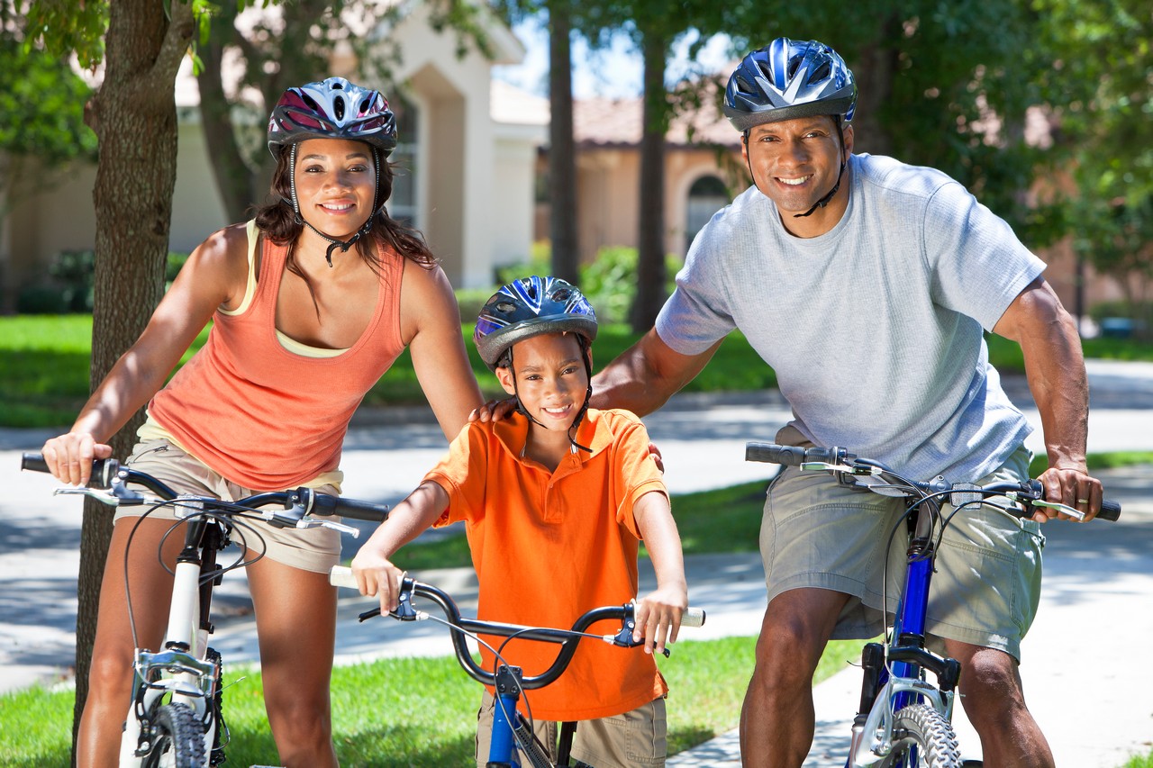 A young African American family, woman, man, father, mother & boy child riding bicycles in the summer